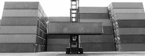 Container handler lifting a shipping container between stacks.