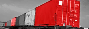 Red and gray shipping containers on a freight train.